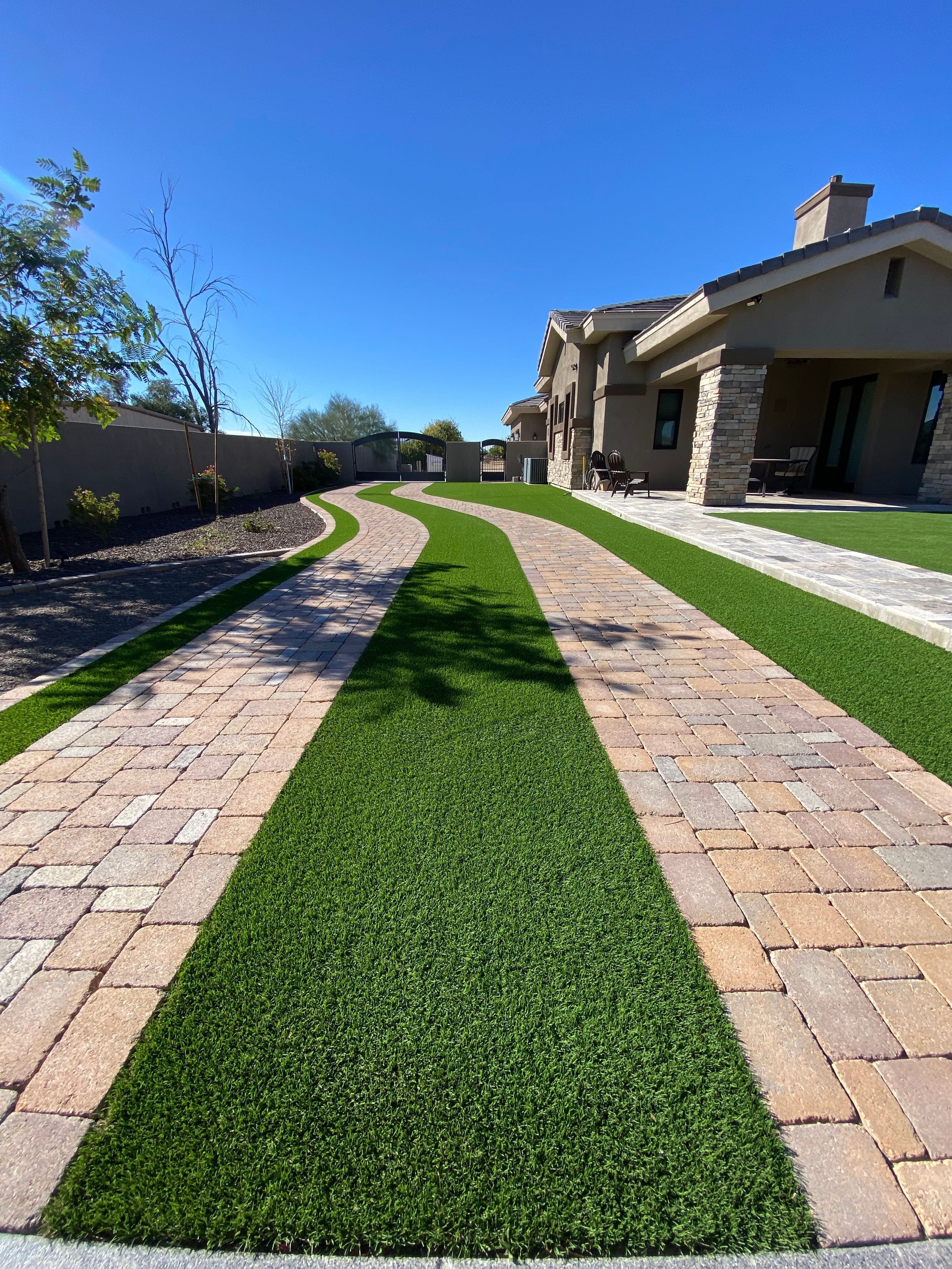 Artificial turf bordered by paver walkways, professionally cleaned by Zeo Turf Cleaning